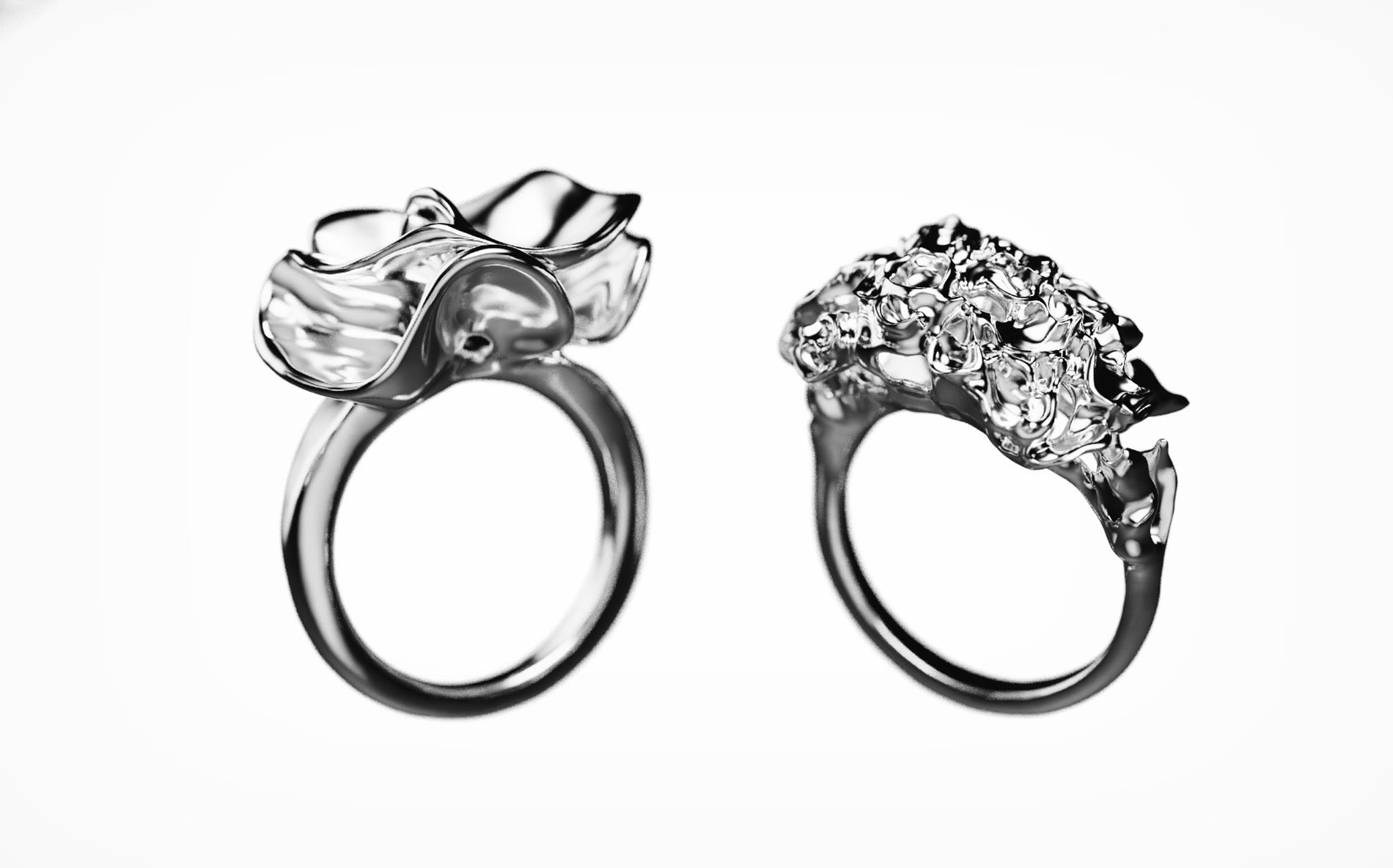 Render of two rings side by side, one a folded petal form, the other a dense mineral cluster