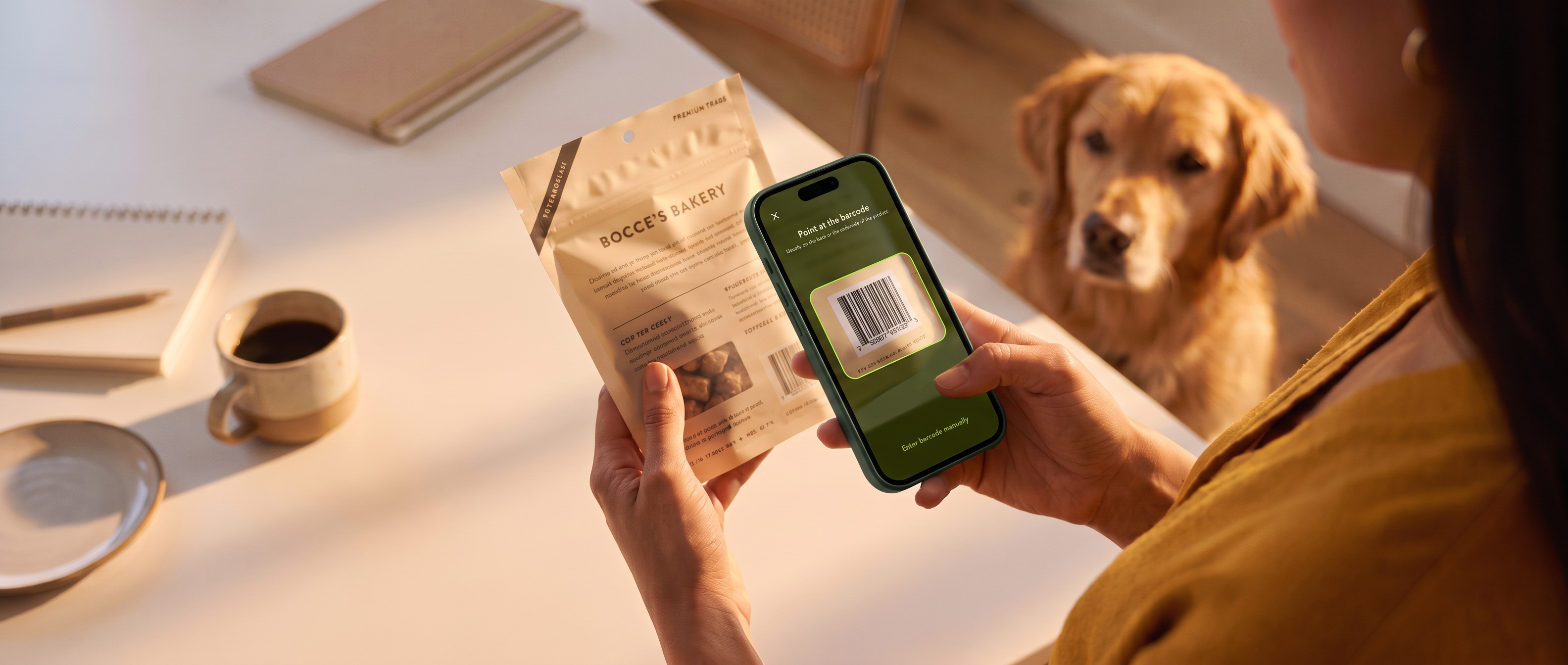 A person scanning the barcode on a bag of dog treats with the Sniffy app while a golden retriever waits