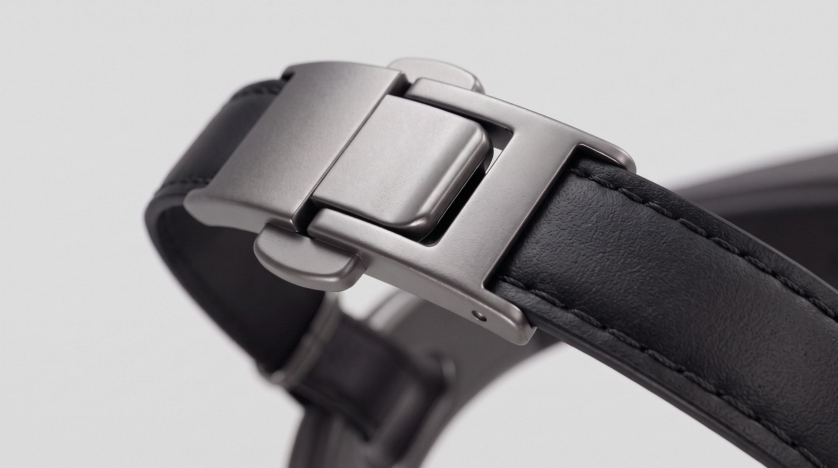 Macro of the brushed metal fold-over clasp closing a stitched black leather strap